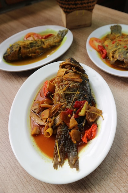 A plate of fish with a yellow sauce and red peppers.