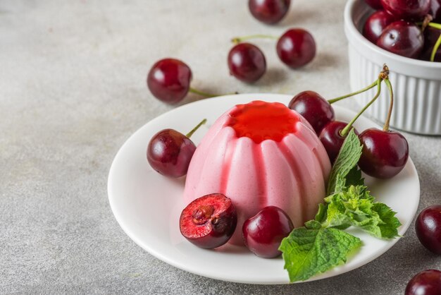 A plate of a flan with cherries on it