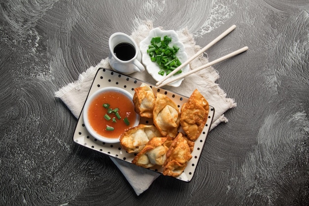 A plate of food with a bowl of sauce and chopsticks on it