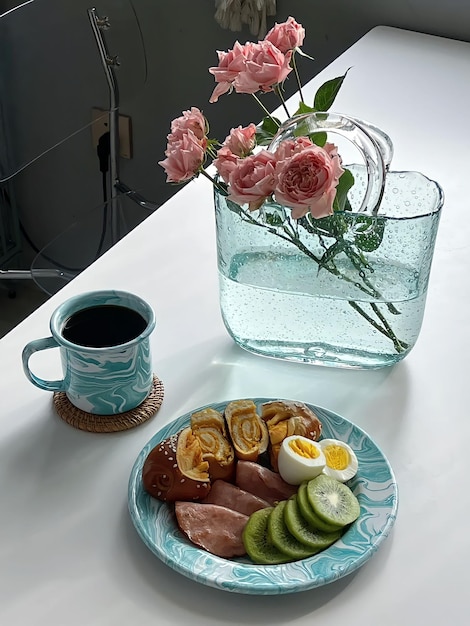 A plate of food with a cup of coffee and a vase of flowers.