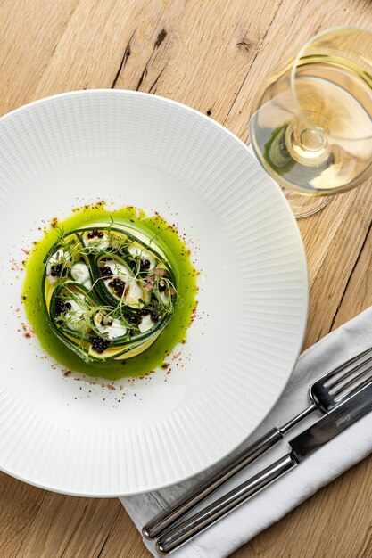 A plate of food with a green sauce on it and a silver fork on the side.