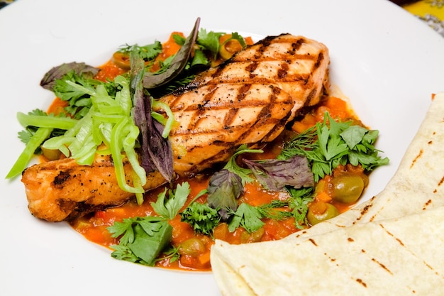 A plate of food with a grilled chicken breast and vegetables.