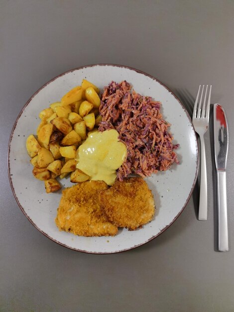 A plate of food with meat and cheese on it and a fork next to it.