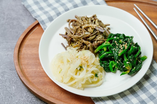 A plate of food with noodles and vegetables on a wooden tray