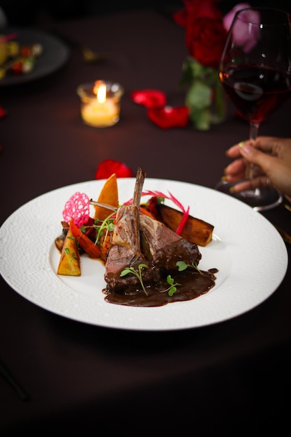 A plate of food with a person holding a glass of red wine