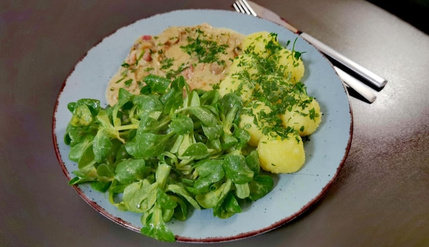 A plate of food with potatoes and greens on it