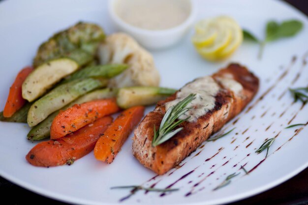 A plate of food with a salmon on it and vegetables on it.