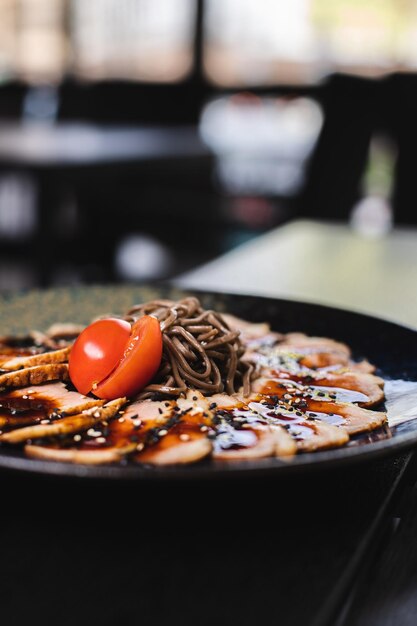 A plate of food with a sauce and a bowl of noodles.