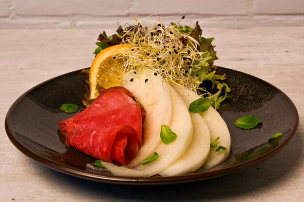 A plate of food with a slice of basterma and galia melon.