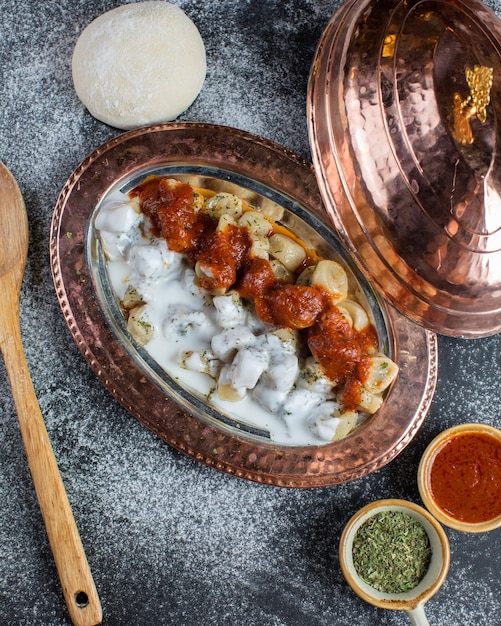 A plate of food with a spoon and a bowl of spices on the side.