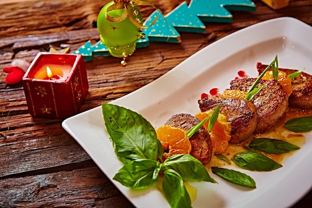 Photo a plate of food with a stick of meat on it and a candle in the background.