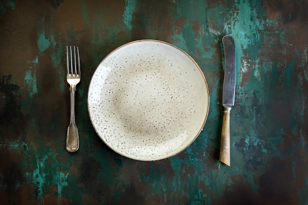 Plate, fork and knife on a rusty metal table