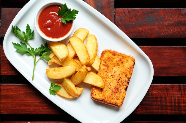 Un piatto di patatine fritte con recupero, fondo in legno