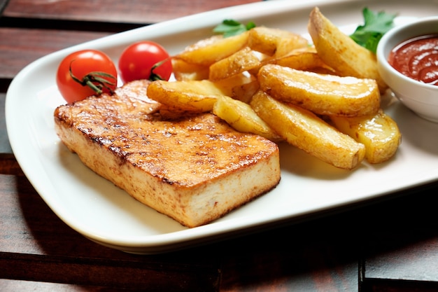 Un piatto di patatine fritte con recupero, fondo in legno