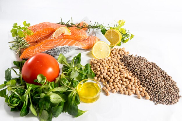 Photo plate of fresh raw salmon fillets with herbs, parsley, lemon and legumes, chickpeas, lentils,