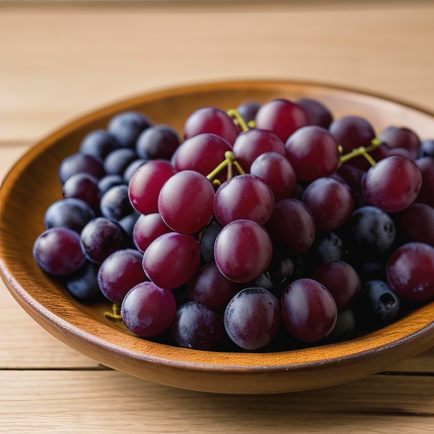 Plate of fresh ripe red grapes on wooden table close up