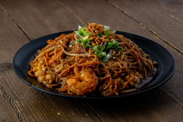 Plate of fresh tasty Mie goreng dish on a wooden table