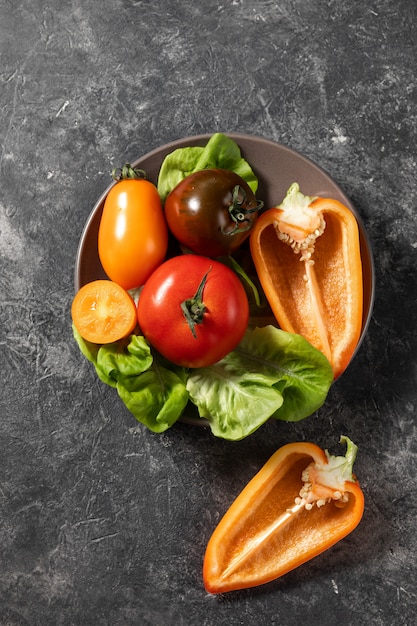 Plate of fresh vegetables on a dark background, top view