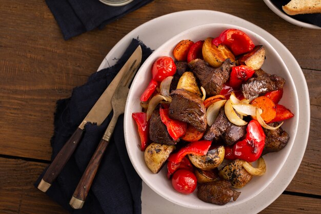 Plate fried beef meat, new potatoes vegetables top view