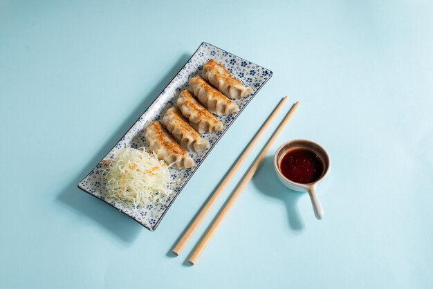 Photo a plate of fried dumplings on clean blue background