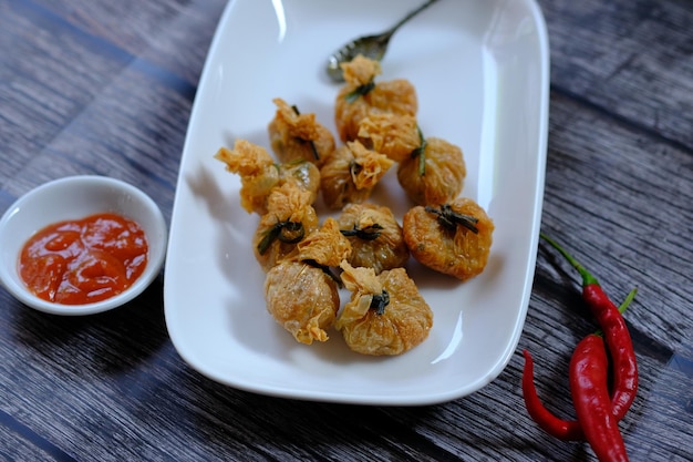 A plate of fried fish with a red chili sauce