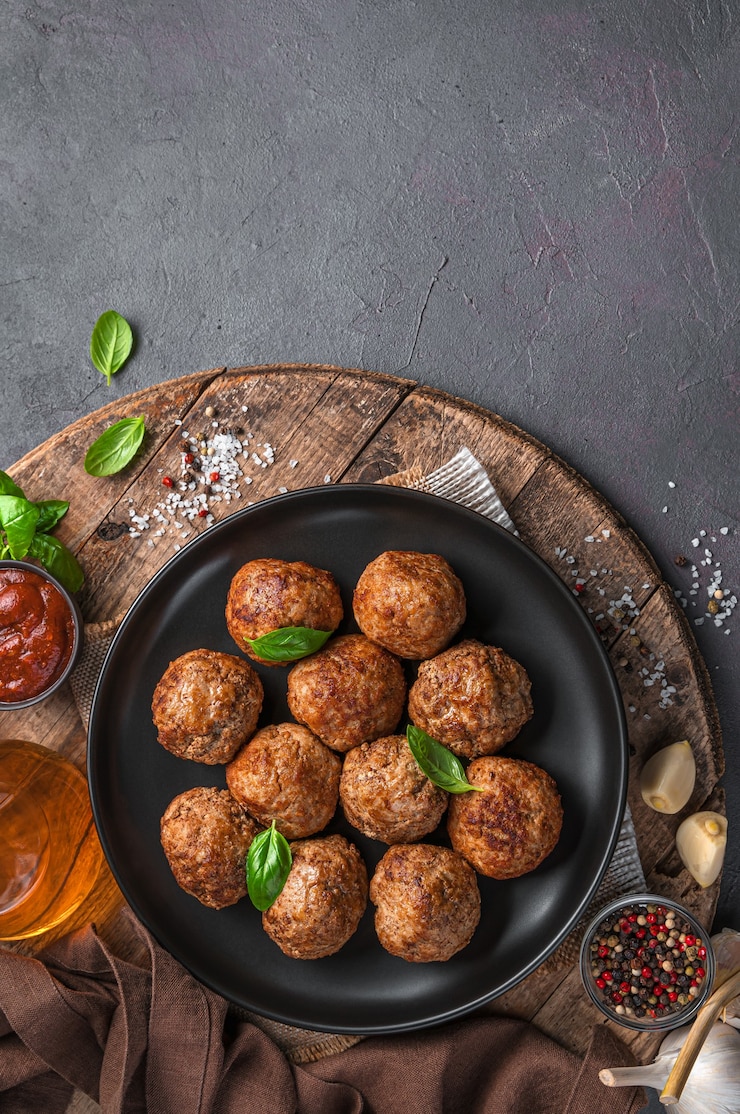 Photo a plate of fried meatballs with basil on a wooden board. vertical view, space for copying.