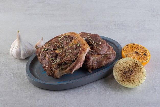 Plate of fried steak with roasted vegetables on stone table.