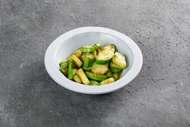 Piatto di zucchine fritte in piatto bianco su sfondo grigio cemento