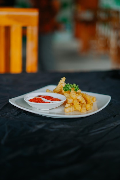 A plate of fries and a bowl of sauce with a red sauce on it.