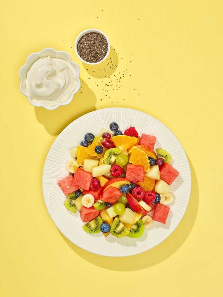 Photo plate of fruit salad on yellow background, top view