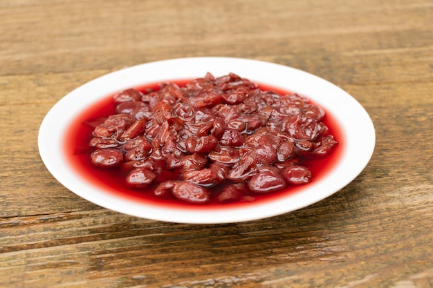 A plate full of cherry jam on wooden background