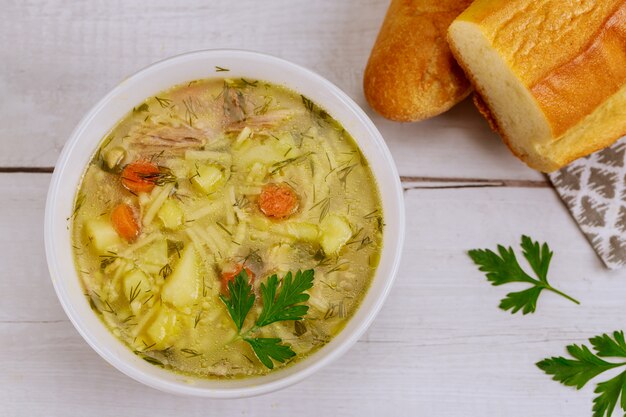 Piatto pieno di zuppa di pasta di pollo con pane