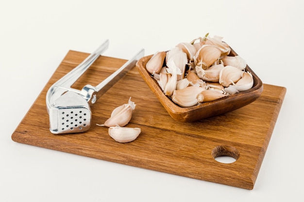 A plate of garlic with squeeze and cutting board isolated on white background