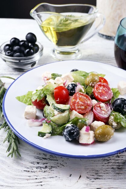 Photo plate of greek salad served with wine and olive oil on wooden table on dark background