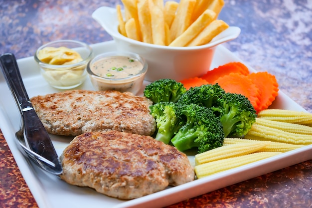 plate of grilled pork with french fries and salad