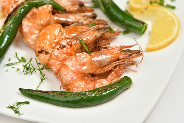 A plate of grilled shrimp with zucchini and lemon wedges.