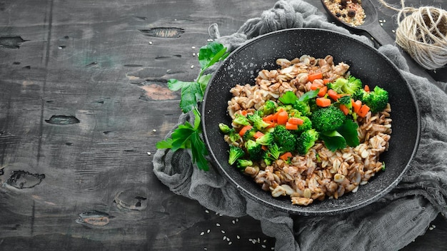 A plate of healthy food Oatmeal with broccoli carrots and parsley Top view On a black background Free copy space