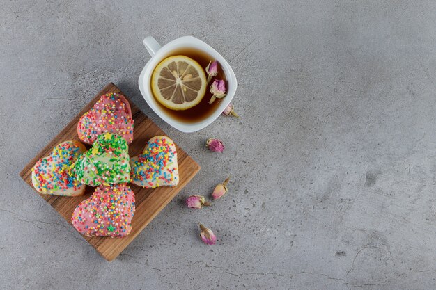 A plate of heart shaped cookies with sprinkles on a stone 