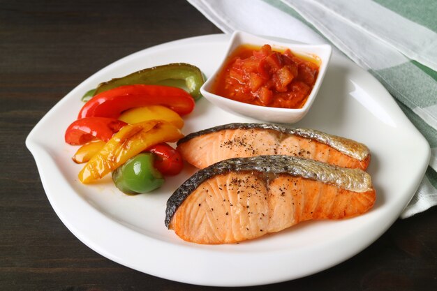 Plate of homemade pan seared salmon steaks with colorful grilled bell-peppers
