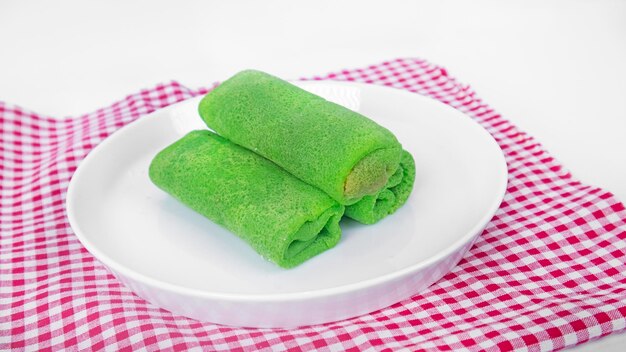 A plate of indonesian Coconut Filled Pandan Pancake Rolls