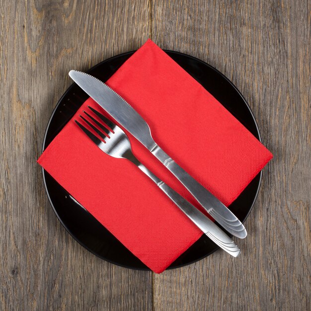 Plate, knfie and fork on a red napkin and black plate