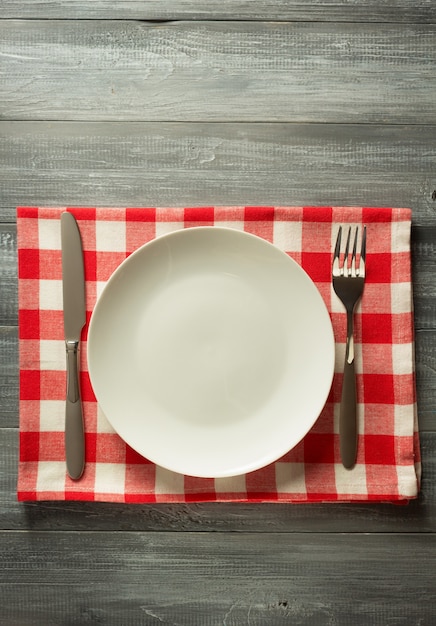 Plate, knife and fork on rustic wooden wall