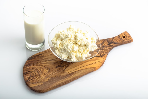 Photo in a plate, large pieces of cottage cheese, a glass with milk, cutting board, isolated background