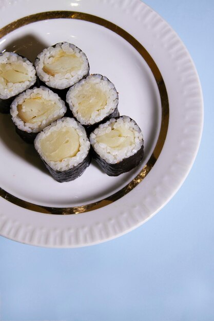 a plate of maki sushi rolls with oilfish on blue background