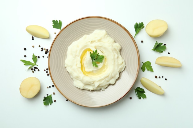 Plate of mashed potatoes and ingredients on white