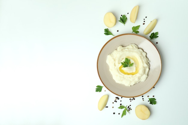 Plate of mashed potatoes and ingredients on white