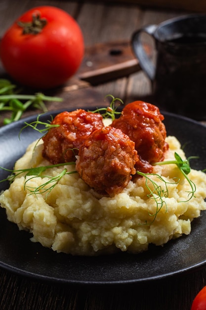 A plate of mashed potatoes with meatballs on top