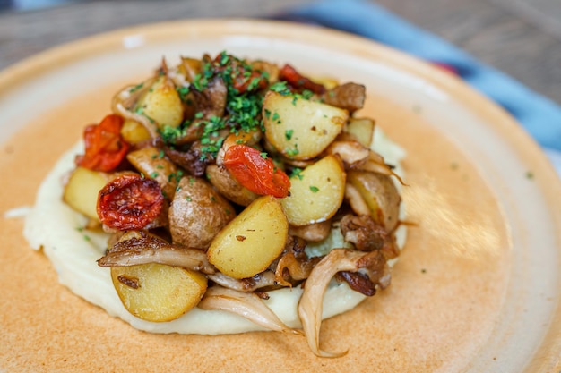 Photo a plate of mashed potatoes with a pile of potatoes and tomatoes.