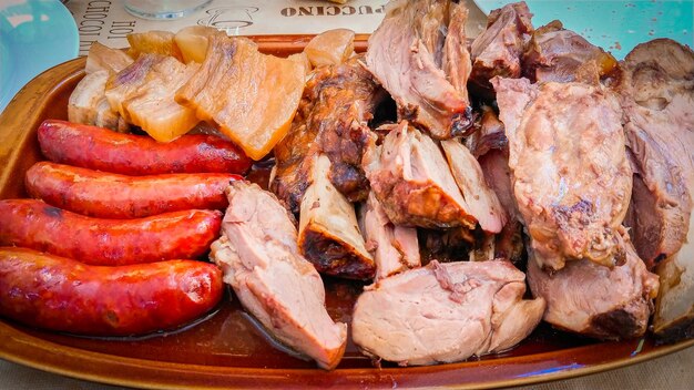 A plate of meat and sausages with a bottle of beer in the background.