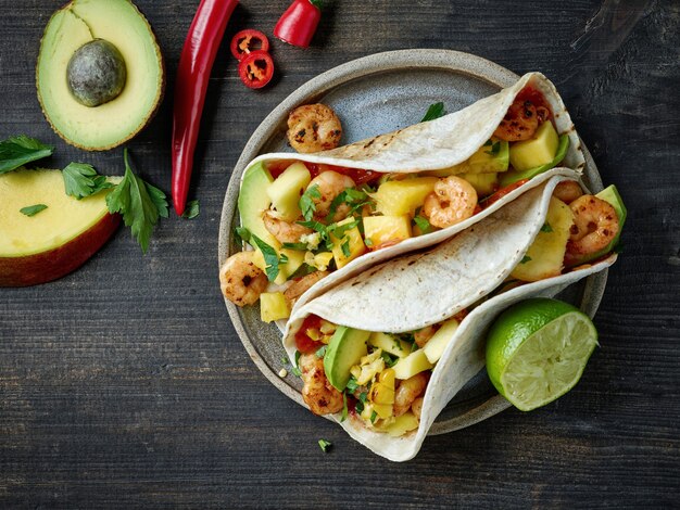 Plate of Mexican food Tacos on black wooden kitchen table background, top view